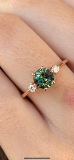 a woman's hand with a green and white diamond ring on her left hand