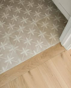 a bathroom floor with white and gray tiles on the bottom, and light wood floors