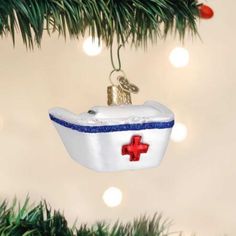 an ornament shaped like a boat with a red cross on it hanging from a christmas tree