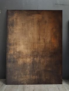 a large brown painting sitting on top of a wooden floor