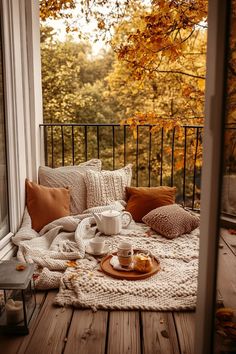 a cozy balcony with fall leaves and coffee on the table in front of an open window