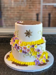 two tiered cake decorated with yellow and purple flowers