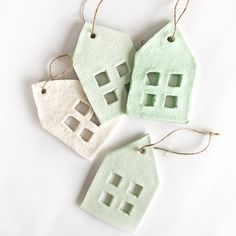 three ornaments made to look like houses hanging from twine