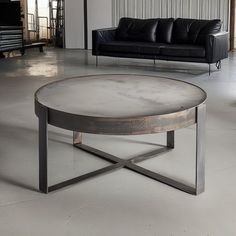 a living room with a couch, table and black leather sofa in the background on concrete flooring