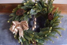 a christmas wreath with bells and pine cones on a chalkboard background, decorated with greenery