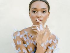 a woman with butterflies on her body posing for the camera and holding her hand to her mouth