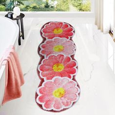 a bath mat with flowers on it is in the middle of a white bathroom floor