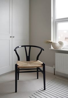 a chair sitting in front of a window next to a radiator and cabinet