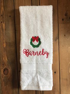 a white towel with a wreath and name on it hanging from a wooden wall next to a pair of scissors