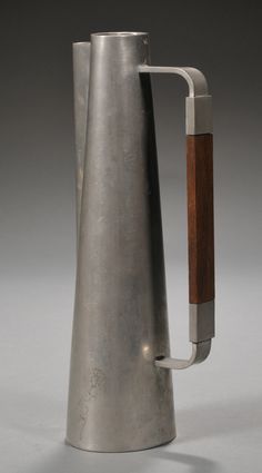 a metal pitcher with a wooden handle on a gray background, it appears to be made out of steel and wood