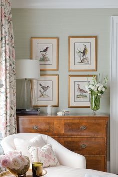 a living room filled with furniture and pictures on the wall above it's dresser