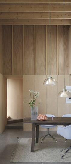 a dining room table and chairs in front of wooden paneled walls with hanging lights