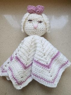 a crocheted stuffed animal with a pink bow on it's head is laying next to a white blanket