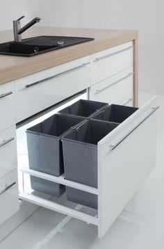 a kitchen with white cabinets and gray bins