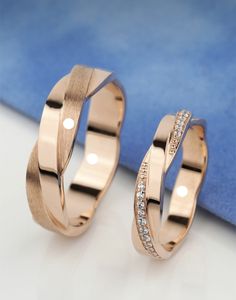 two rose gold wedding rings with diamonds on the inside and outside, sitting next to each other