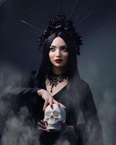 a woman holding a skull in her hand and wearing a crown on top of her head