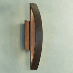 a wall mounted clock on the side of a blue wall with a curved metal frame