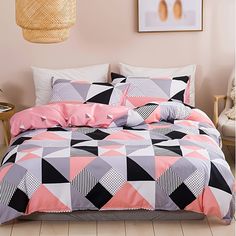 a bed covered in pink and black comforter next to a painting on the wall