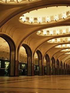 an empty train station with lots of lights on the ceiling and arches in the middle