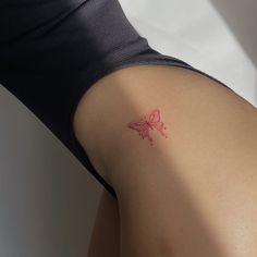 a red butterfly tattoo on the back of a woman's left arm and shoulder