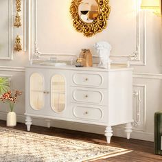 a white cabinet with gold accents and a mirror on the wall in a living room