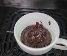 a white cup filled with sauce sitting on top of an oven