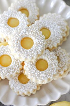 small cookies with powdered sugar on them are arranged on a white plate next to two lemons