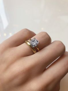 a woman's hand with a diamond ring on top of her finger and gold band