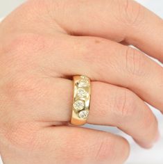 a person's hand with a gold ring on it and three diamonds in the middle