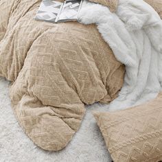 an unmade bed with blankets and pillows on top of it, next to a stuffed animal