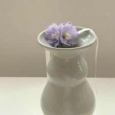 a white vase with purple flowers in it