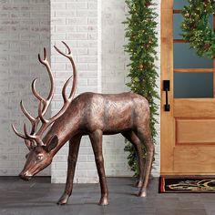 a statue of a deer eating grass in front of a door