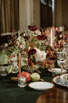 the table is set with plates, glasses and flowers