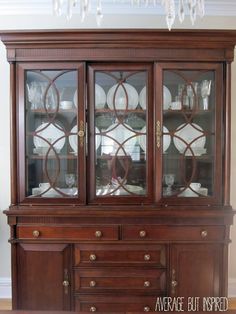 a china cabinet with glass doors and plates on top