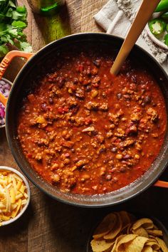 a pot filled with chili and tortilla chips on top of a wooden table