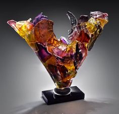 a colorful glass sculpture sitting on top of a black table next to a gray wall