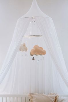 a white canopy bed with three clouds hanging from it