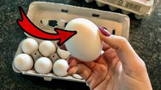 a person holding an egg in their hand with the red arrow pointing to it on top