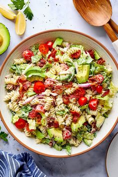 a bowl filled with pasta salad next to sliced avocado