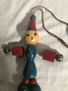 a wooden toy with bells attached to it's head and neck, sitting on a white sheet