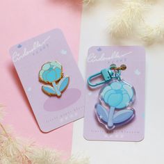 two blue and pink pin badges sitting next to each other on top of a table