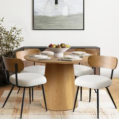 a dining room table with four chairs and a bowl of fruit on the centerpiece