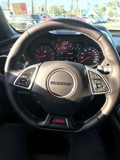 the interior of a car with steering wheel controls and dashboard gauges, including an electronic display