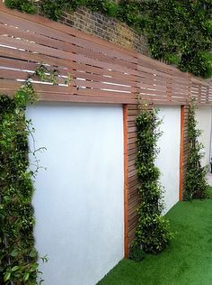 an outdoor living area with artificial grass and wood slatted fenced in to it