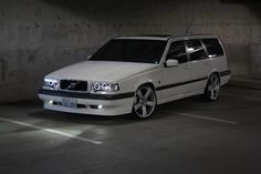 a white volvo wagon parked in a parking garage with its lights on and the door open