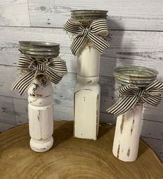 three mason jars with bows on them sitting on top of a tree stump