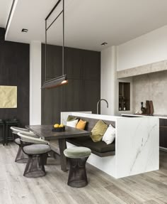 a modern kitchen with an island table and bench in the center, along with two stools