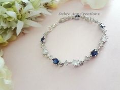 a bracelet with blue and white stones sits on a table next to some flower petals