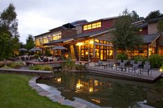 a large house with an outdoor patio and dining area next to a pond at night