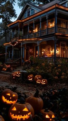 pumpkins lit up in front of a large house with lights on the porch and windows